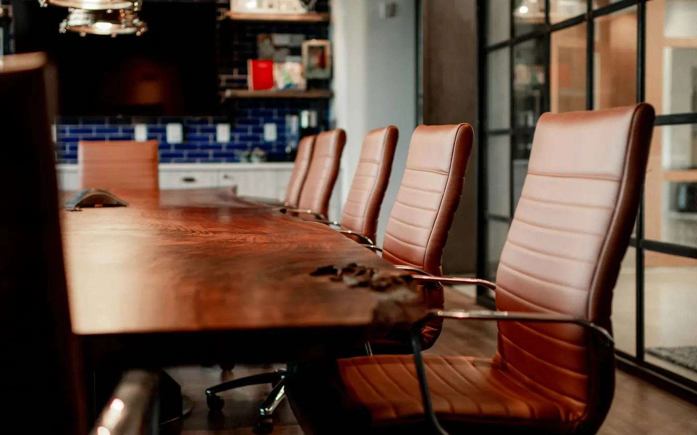 Sala de reuniões com mesa de madeira e cadeiras de couro